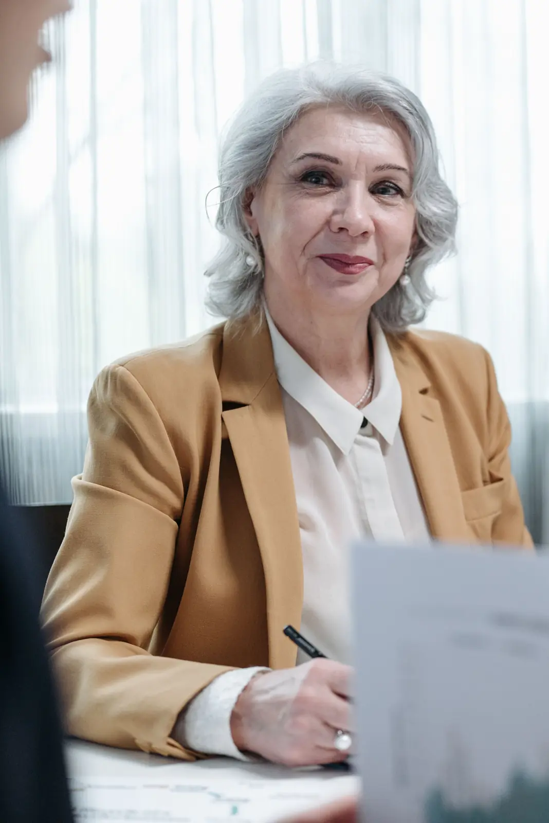 A business owner smiling while she works through papers at a desk.