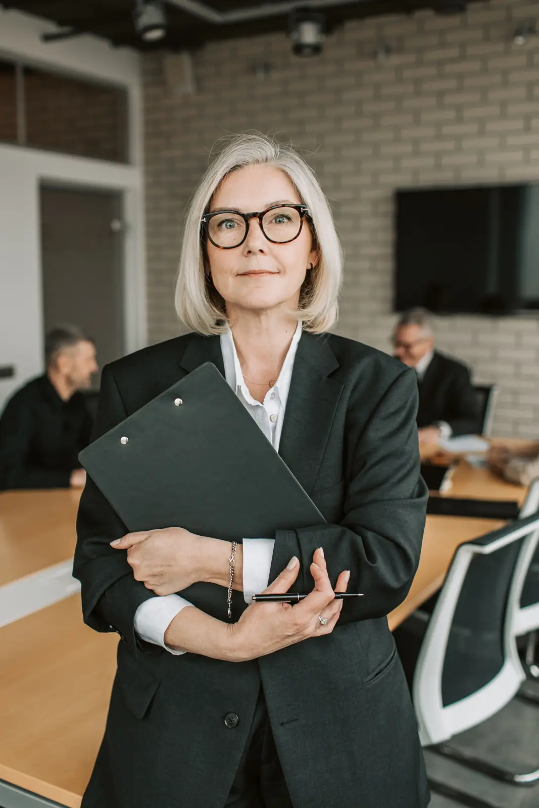 A senior leader holding a clipboard in a meeting room.